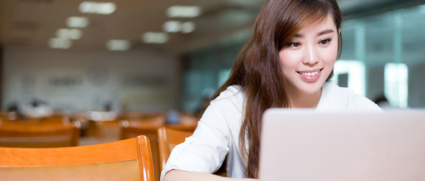 a woman in a classroom using a laptop while smiling