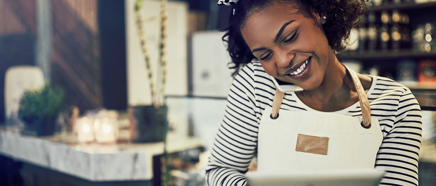 woman in a grocery store, taking a customer's order over the phone and writing down the information on a tablet
